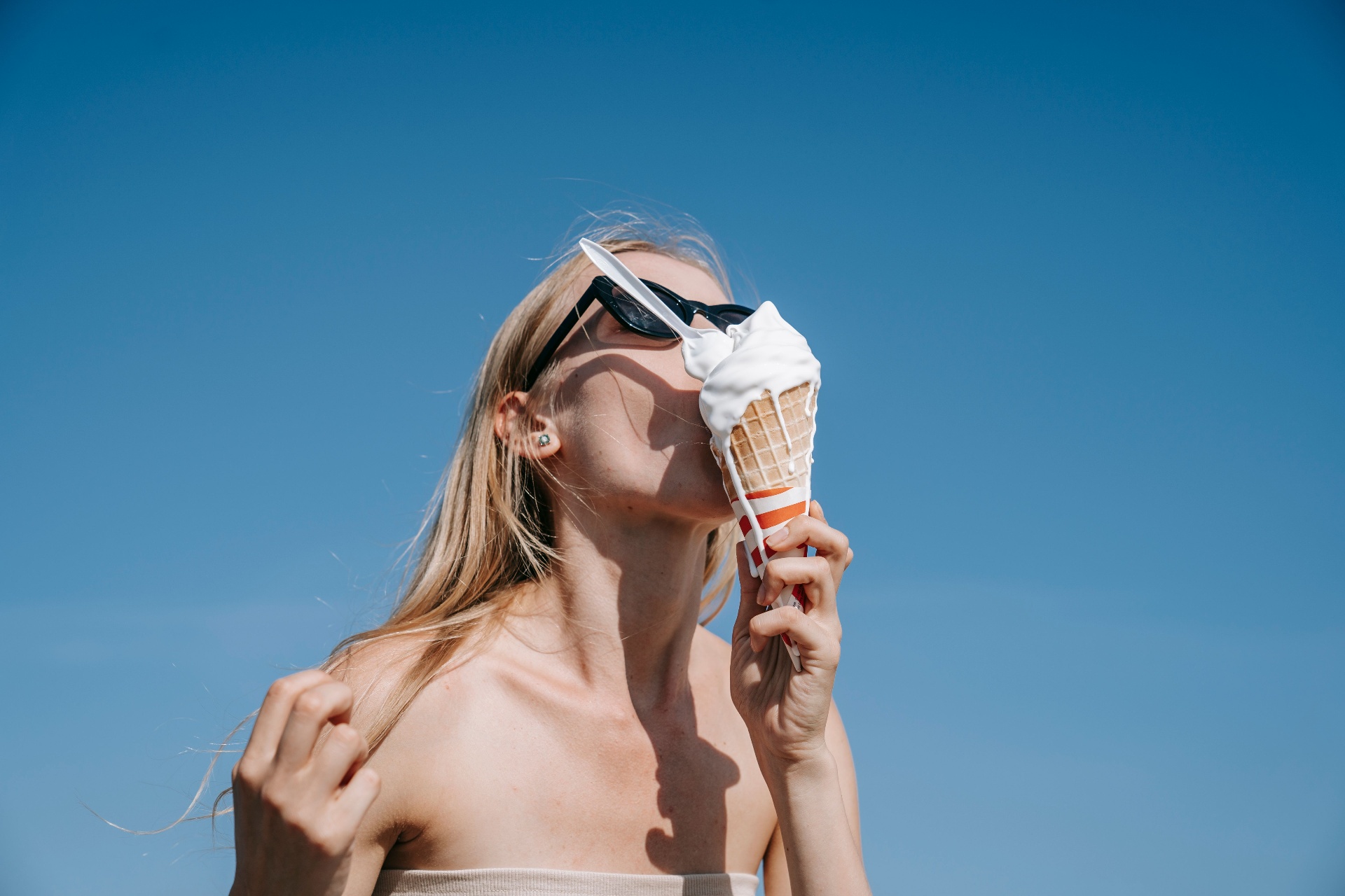 Mujer comiendo helado bajo el sol